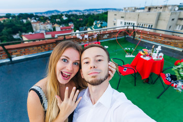 Fototapeta na wymiar selfie couple in love. girl hugs guy and shows engagement ring o