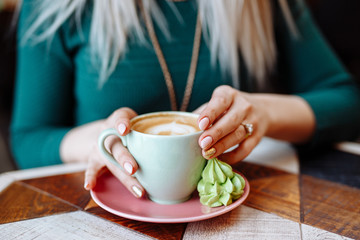 The girl is holding a Cup of cappuccino coffee. Hands close up.