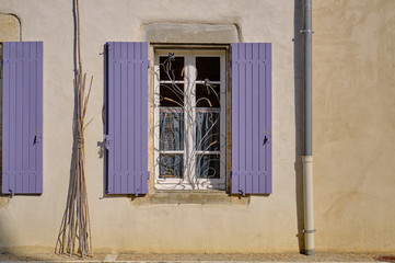 French window with mauve shutters.  Texture terracota walls, and wrought iron display in window