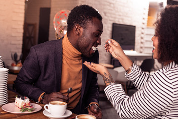 Delighted positive man trying a cake from his girlfriend