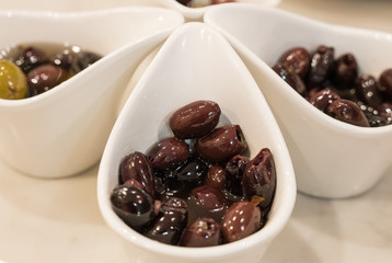 Close up of marinated olives in modern white bowls.