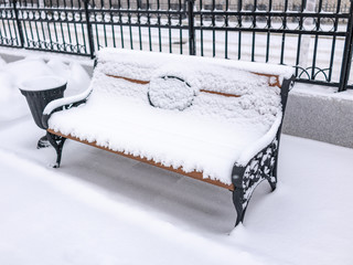 Empty bench in the winter park covered with fresh white snow