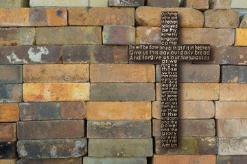 Wooden cross with the Lord's prayer on  old brick black wall background