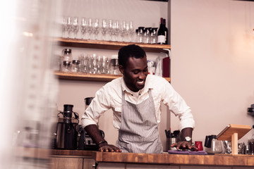 Delighted cheerful man working in his own cafe