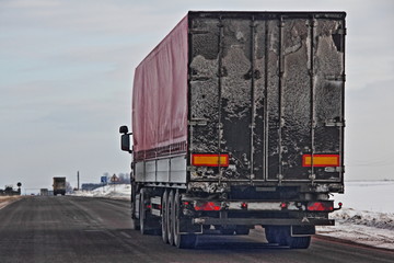 Rear view on european semi-trailer truck on asphalt winter road - delivery, logistics, transportation