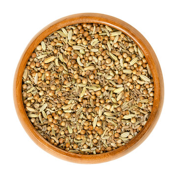 German bread spice mixture in wooden bowl. Mix of anise, fennel, coriander and caraway seeds. Used as digestive aid in bread recipes. Isolated macro food photo, closeup from above on white background.