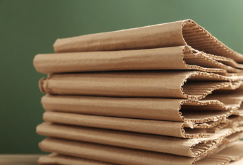 Stack of cardboard against green background, closeup. Recycling concept