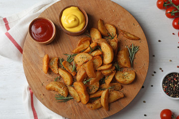 Baked potatoes served with rosemary, ketchup and mustard on table, top view