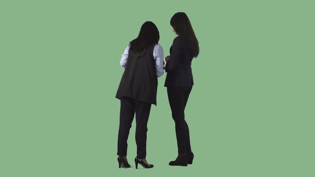 Two young women in office clothes are standing with documents. Back view. Transparent background