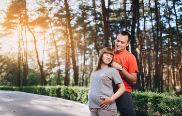 Fototapeta premium A stylish guy and a pregnant girl are standing in the forest and hugging. Pregnancy. Love of married people.