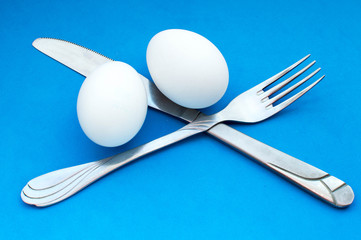 Knife, fork, two white eggs. Cooking breakfast