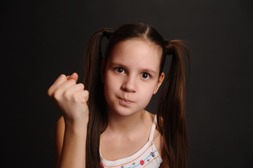 little girl shows fist on black background