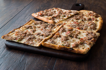Turkish and Arabic Traditional Ramadan Bread Sliced Etli Ekmek Kebab with Minced Meat (Pide or Lahmacun Kebap) serving on wood by Konya