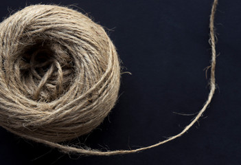 Coil of old twine, or natural jute, wool linen on black surface. Used for DIY, wrapping of gifts and handmade 