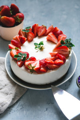 Delicate cheesecake with fresh strawberries on a gray background. Homemade cheese and cream cake decorated with berries
