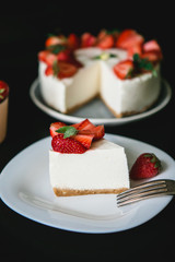 Cheesecake with strawberries on a black background. A piece of cake with strawberries and cream