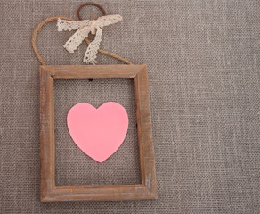 Pink heart in wooden border on canvas