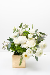 White floral bouquet in a golden vase on white background