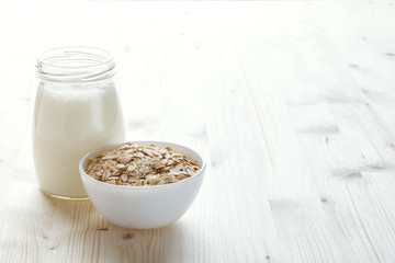 bottle of milk and oat flakes in a bowl, vegetarian or vegan food, healthy breakfast, copy space