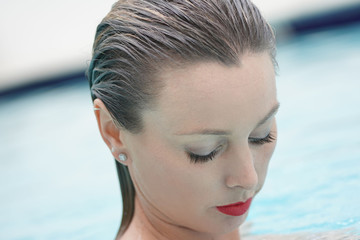 Portrait of stunning woman in swimming pool with red lipstick