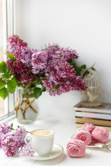 Fototapeta na wymiar Bouquet of lilacs, cup of coffee, homemade marshmallow. Romantic spring morning. Selective focus