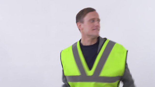 Young handsome man in construction cloth and hat dancing jumping and when saw his boss stop dance and became very serious and shy. Shooting in the studio on a white background.