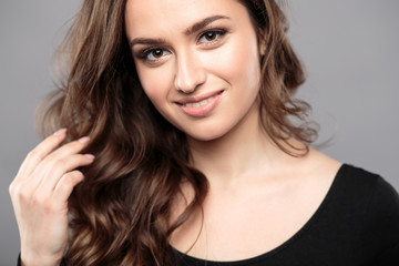 Fototapeta premium Brunette girl with healthy curly hair and natural make up . Beautiful model woman with wavy hairstyle .Care and beauty
