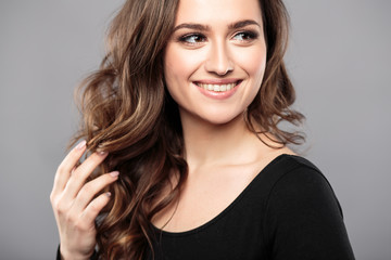 Brunette girl with healthy curly hair and natural make up . Beautiful model woman with wavy hairstyle .Care and beauty