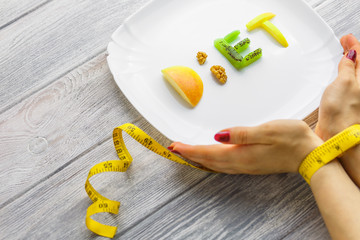 fruit on a plate of a word diet of apple, kiwi, carrots, nuts and raisins.