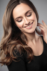 Fototapeta premium Brunette girl with healthy curly hair and natural make up . Beautiful model woman with wavy hairstyle .Care and beauty