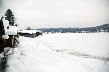Frozen river covered with ice and snow in the village at winter.
