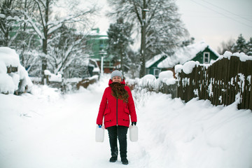 Woman on the street in the Russian village at snowy winter.