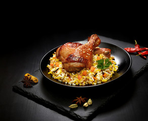 grilled chicken legs with sesame and rice on a black background