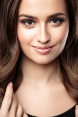 Fototapeta premium Brunetka dziewczyna z zdrowe włosy kręcone i naturalny makijaż. Piękny model kobiety z falowaną fryzurą. Pielęgnacja i uroda