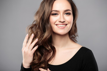 Brunette girl with healthy curly hair and natural make up . Beautiful model woman with wavy hairstyle .Care and beauty