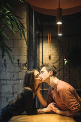 Fototapeta na wymiar Theme love and holiday Valentines Day. couple of college students together in Caucasian heterosexual lovers winter inside the cafe sit at empty table embrace. Emotion happiness and love