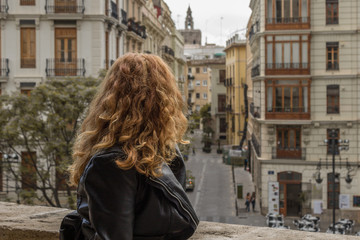 Mujer mirando por el balcón en Valencia