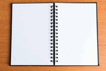 Open white paper notebook on a warm wood desk background