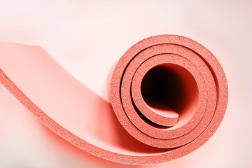 Lightweight foam living coral roll. Yoga mat as swirle on isolated white. Concept.