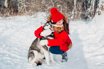 Young girl with her husky dog in winter park. Domestic pet. Husky