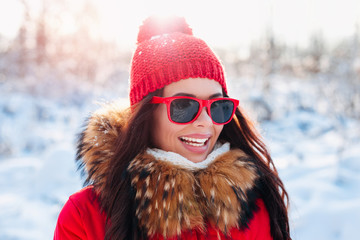 Smiling woman with red sunglasses on winter background