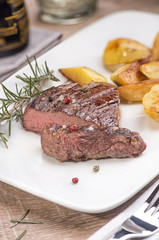 Beef steak with fried potatoes in slices on a white rectangular plate in a restaurant.