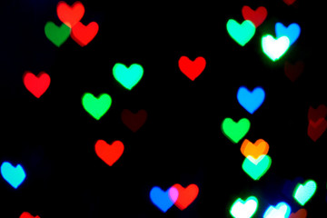 Fototapeta na wymiar Multi colored blurred lights in the shape of hearts in the dark.