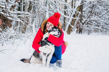 Fototapeta na wymiar Young girl with her husky dog in winter park. Domestic pet. Husky