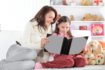 charming mother and daughter reading a book sitting on the couch.photo with copy space