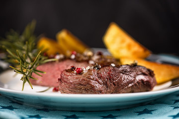 Beef steak with fried potatoes and rosemary in a bowl on a white plate with stars.