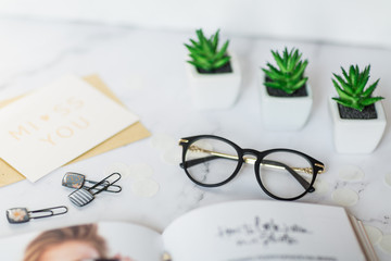 Desk workspace with magazine, card, glasses, succulent on marble background. Business still life....
