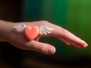 Pink heart with wings in the hands Love Carry Valentine