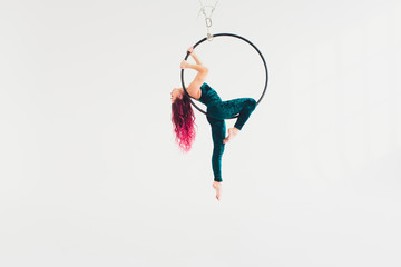 A young girl performs the acrobatic elements in the air ring. Studio shooting performances on a white background. © Евгений Вершинин