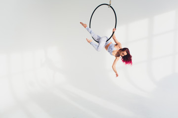 young redhead woman performs acrobatic elements in the air ring on a white background. © Евгений Вершинин